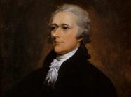 Alexander Hamilton Sits in a dark suit and looks off to the left. 
