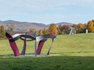 view of multiple sculptures in the park in front of a mountainous fall landscape. 