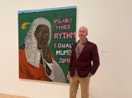 Jeffrey Magid standing in front of Henry Taylor's / was King When I Met the Queen, Syllable x Rythm Equals Mumbo Jumbo, 2013.