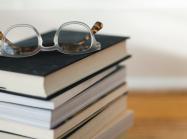 stack of books with pair of reading glasses on top