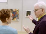 Steve Martin looks closely at work of art on wall