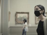 woman in mask looks at painting in the met