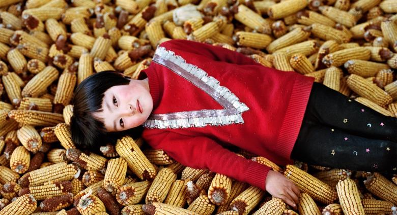 Xiaoxiao Xu photograph of a young chinese girl laying in pile of corn