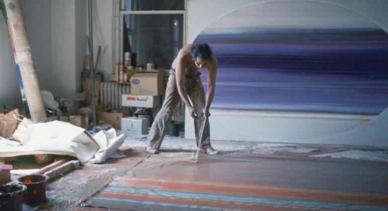 Ed Clark painting on the floor using a broom