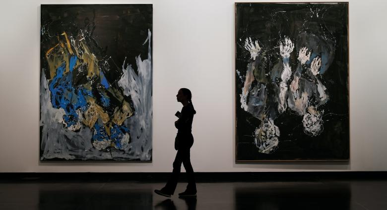 a silhouetted figure walks between two large abstract paintings