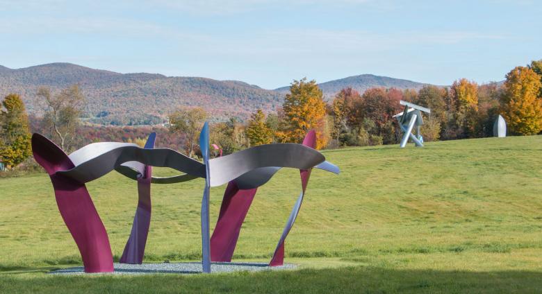 view of multiple sculptures in the park in front of a mountainous fall landscape. 