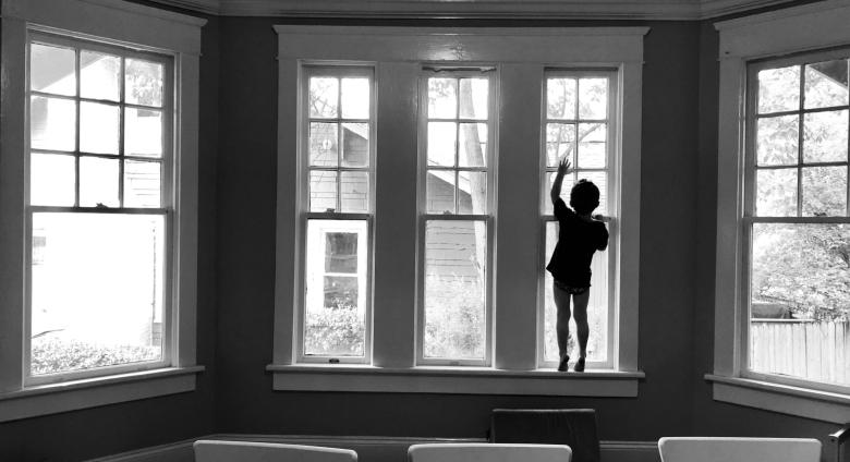 the silhouette of a child standing in a bay window