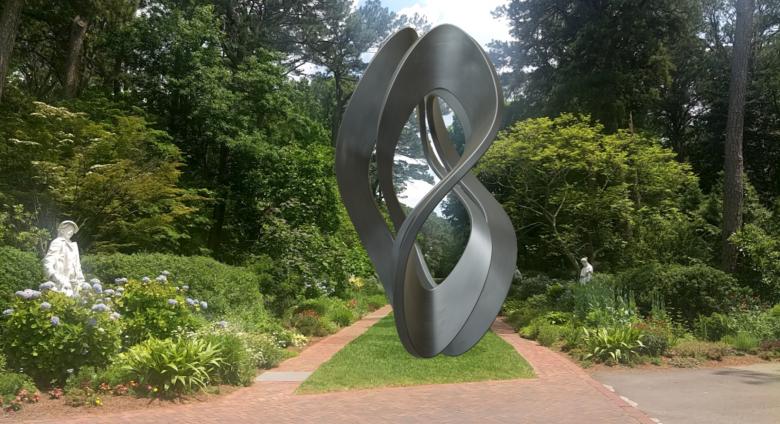 a photo of a large metal sculpture in a twisted organic form in a lush garden setting