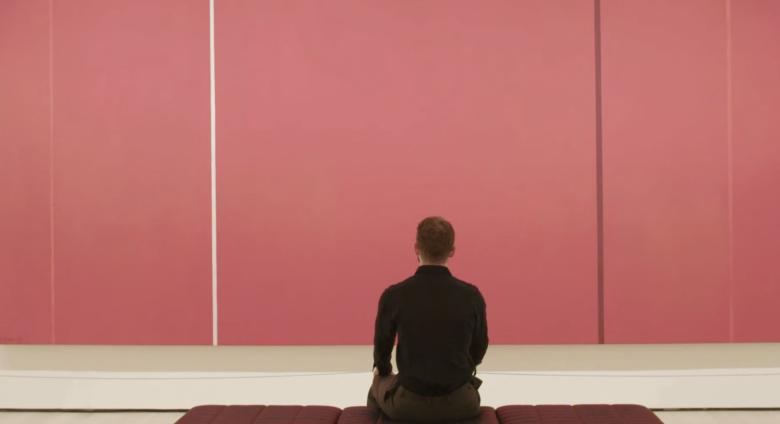 man sitting in front of pink canvas