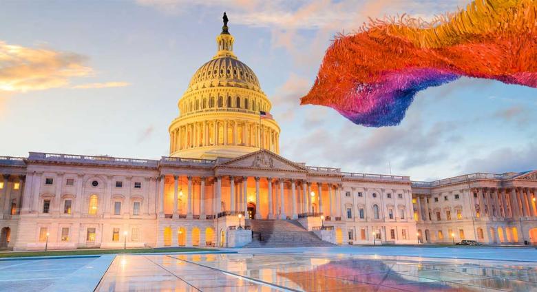 the capitol building with waving rainbow of fabric strips floating in front of it