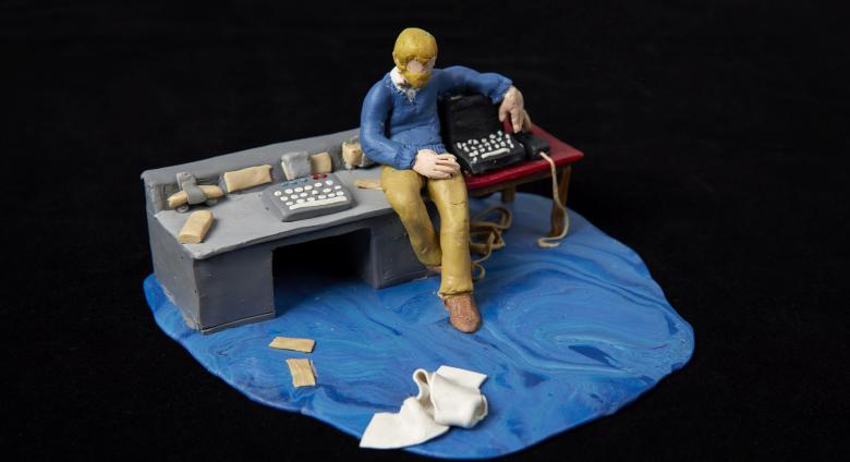 small model of a man at a desk with blue carpeting