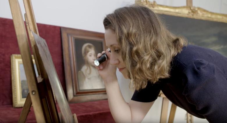 expert examines painting with flashlight
