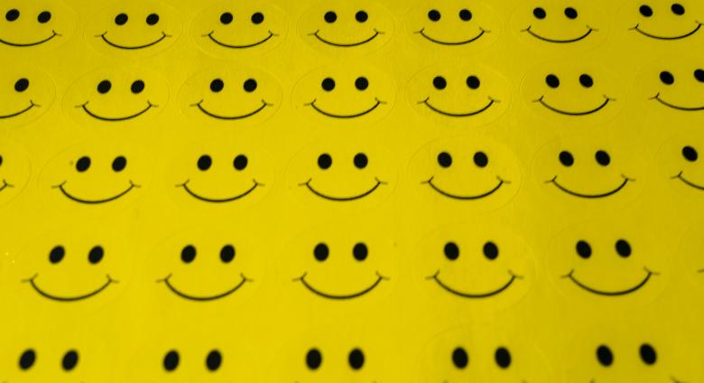 a sheet of yellow fabric with rows and rows of smiley faces
