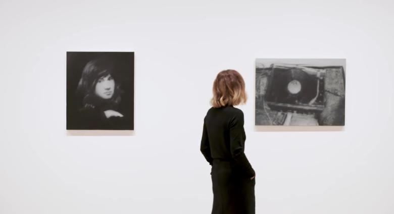 Curator walks through gallery of black and white images.