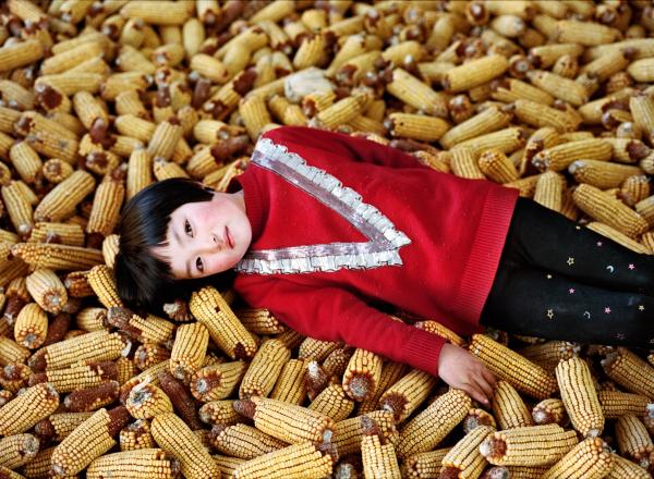 Xiaoxiao Xu photograph of a young chinese girl laying in pile of corn