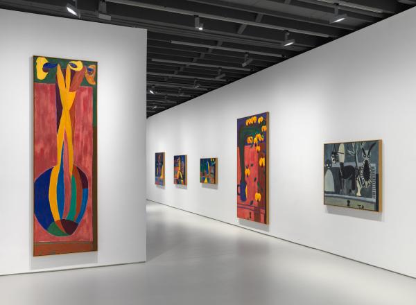 installation view, brightly colored tall paintings in a gallery with white walls