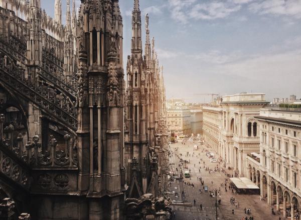 photograph of a dark gothic cathedral in the foreground and a light city behind it