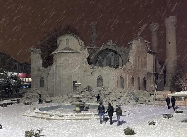 People walk next to a mosque destroyed by an earthquake in Malatya, Turkey, Monday, Feb. 6, 2023. A powerful quake has knocked down multiple buildings in southeast Turkey and Syria and many casualties are feared. (DIA images via AP)