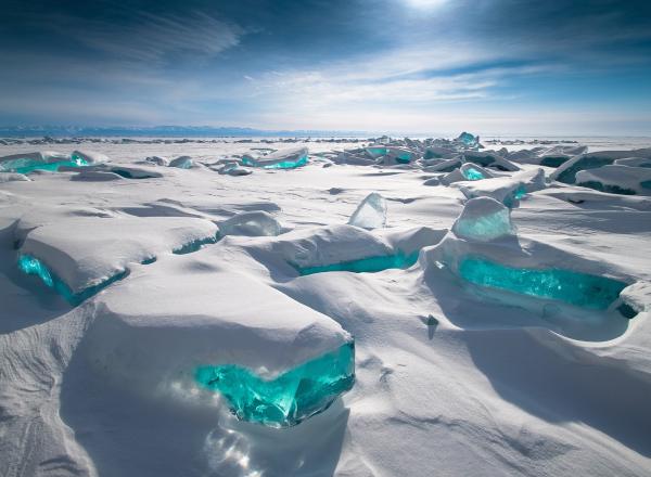 a snowy landscape with bit of brilliant blue ice