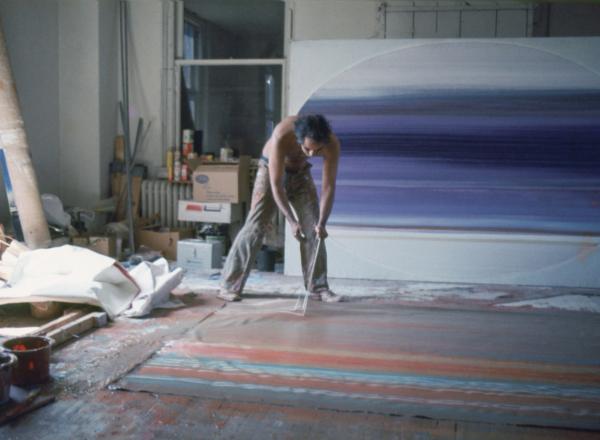 Ed Clark painting on the floor using a broom