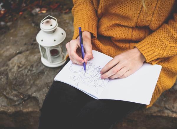 a photo of a person drawing in a journal