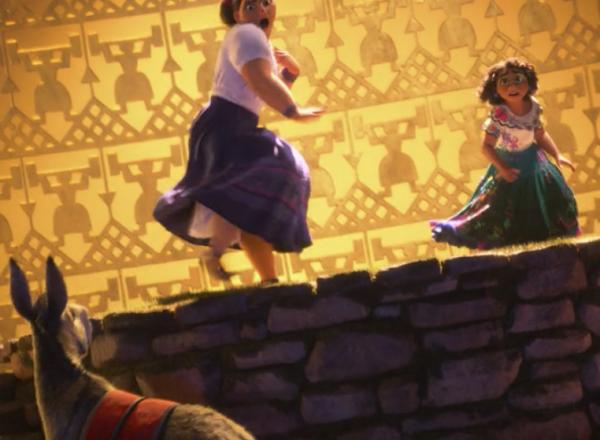 An Encanto film still featuring Louisa and Mirabel standing in front of a golden, geometric background inspired by ancient figurines from the region of current-day Colombia.