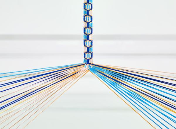 Image of japanese silk braiding in progress. With yellow and two shades of blue silk threads