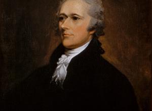 Alexander Hamilton Sits in a dark suit and looks off to the left. 
