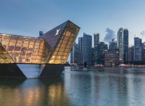 Illuminated polyhedral building Louis Vuitton over the water at Marina Bay in the evening, with skyscrapers of the Central Business District in the background, Singapore. License