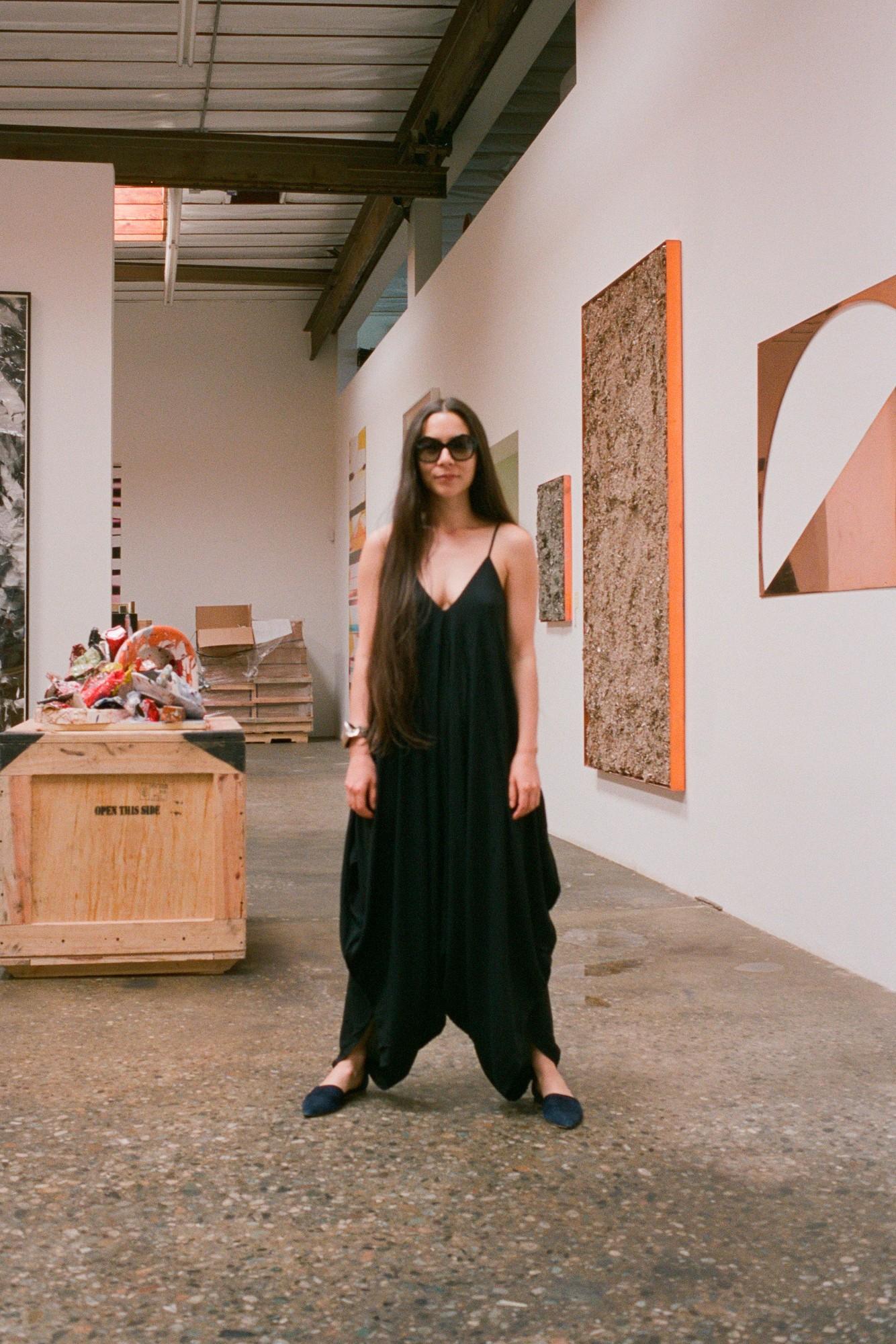 Walead Besht photograph portrait of a woman in large sunglasses and chic black outfit in an art gallery