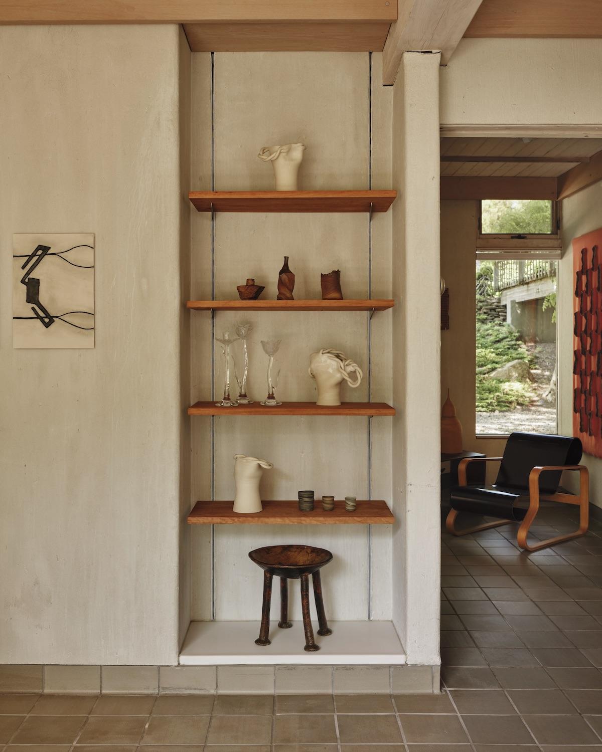 A Summer Arrangement: Object & Thing at LongHouse. LongHouse, East Hampton, New York. Photo by Adrian Gaut. Works pictured: [on wall] Enrico David, Untitled (2014); [shelves] ceramics by Laird Gough, Ludmilla Balkis and Jennifer Lee; glass Giardino candleholders by Sophie Lou Jacobsen; a wooden stand from the collection at LongHouse.