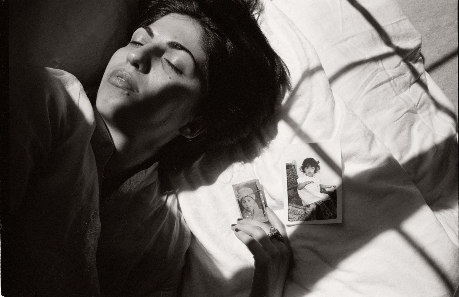 photograph of woman on a bed holding two photographs