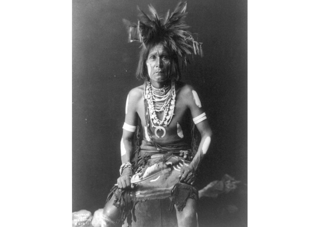 Snake priest. Native American man seated, three-quarter-length, facing front, 1900.