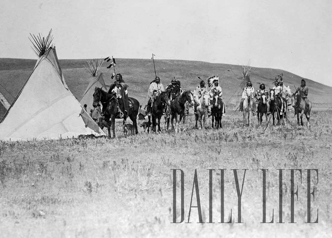 Landscape with four tipis, eleven Atsina Indians on horseback, three women, a child, and two dogs, Montana, 1908.
