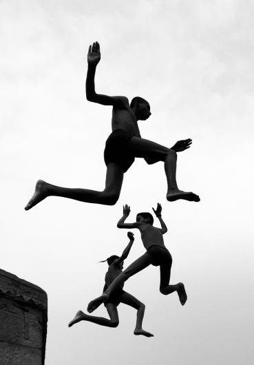 black and white photograph of three figures jumping in the air