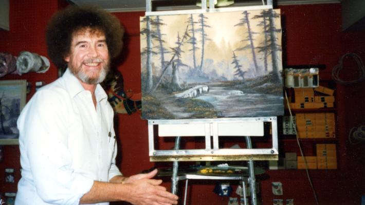 5. Bob Ross- Happy Accidents, Betrayal & Greed - Production Still of Bob Ross with a finished painting.