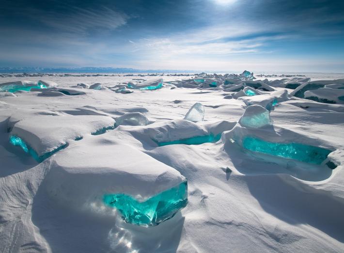 A snowy landscape with bits of vibrant blue ice