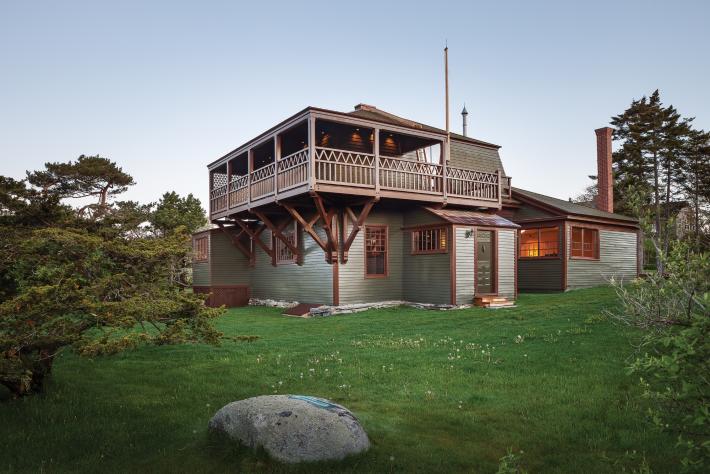 a grey cape cod style house on a green lawn