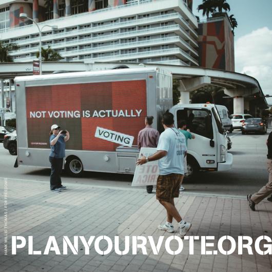 plan your vote .org poster with a photo of a truck that says "not voting is actually voting" on its side