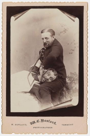 vintage black and white photograph of a man pretending to saw the head off of another man