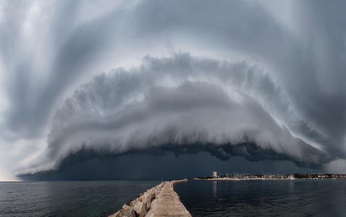 Photograph of a large cloud over a bay and city