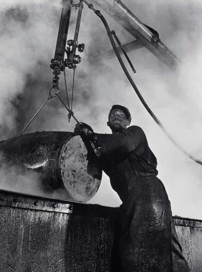 Gordon Parks, The cooper's room where the large drums and containers are reconditioned. Here a workman lifts a drum from a boiling lye solution which has cleaned from it grease and dust particles," March 1944.