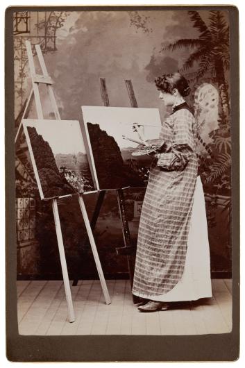 black and white photograph of a woman painting at two easels