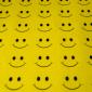 a sheet of yellow fabric with rows and rows of smiley faces